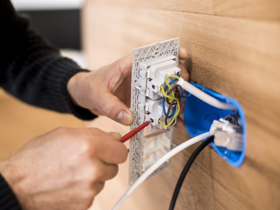 electrician inspecting an outlet in a home